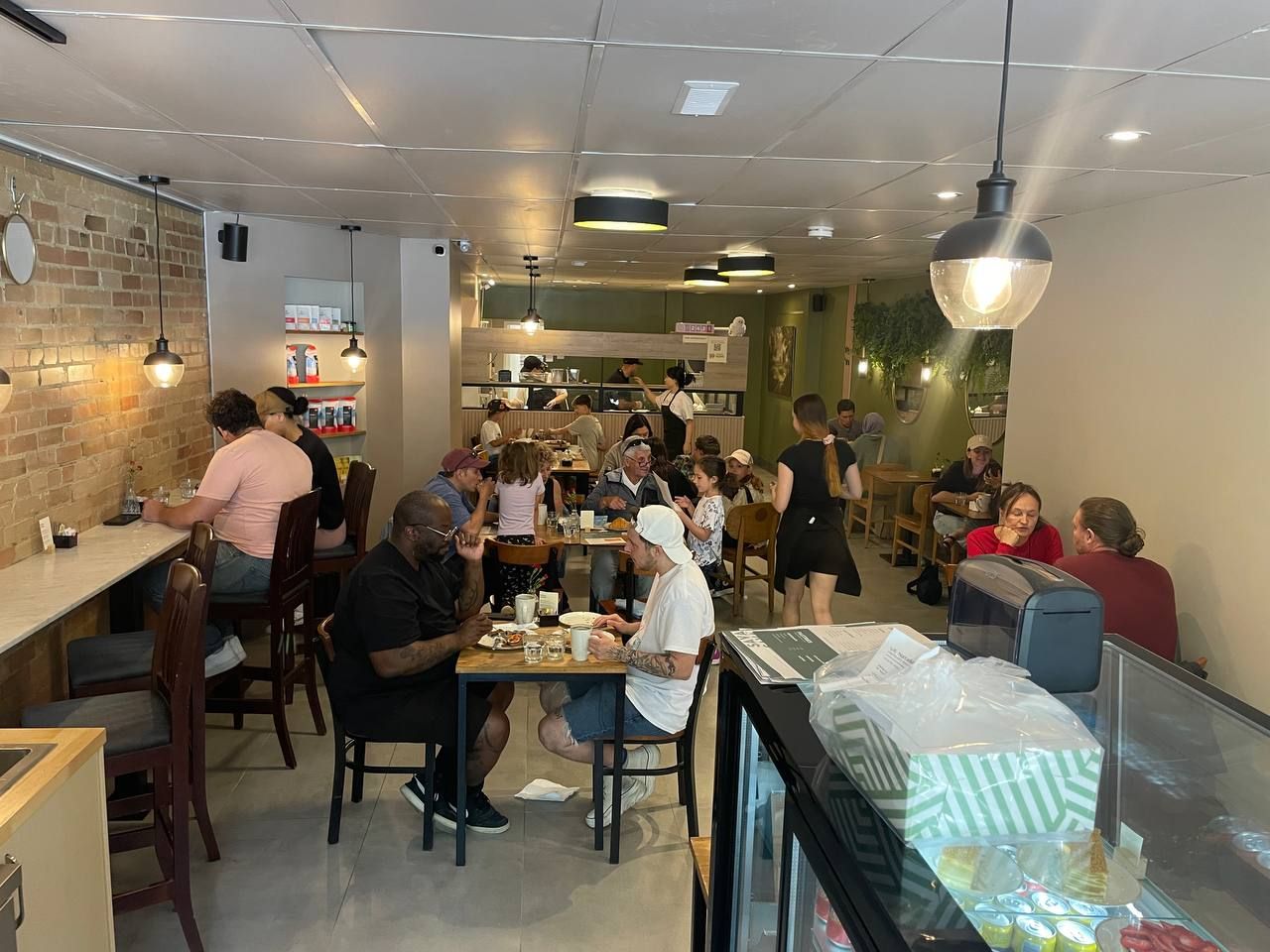 Guests filling the tables in a SAVA dining room with a brick wall and pendant lights